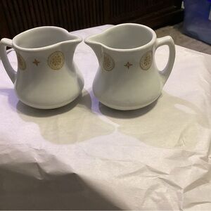 Two Shenango open creamer cups with gold design.